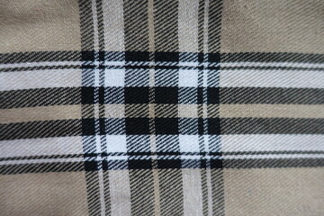Top view of beige, black and white cotton flannel tartan fabric