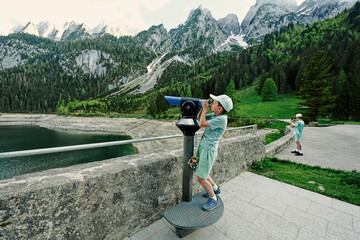 Brothers look at panoramic telescope overlooking in Vorderer Gosausee, Gosau, Upper Austria.