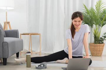 Yoga exercise concept, Young Asian woman doing yoga exercise with tutorial training online at home