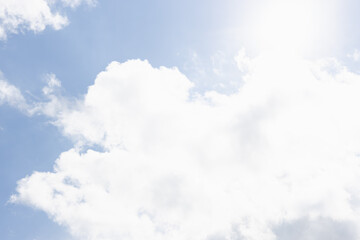 Beautiful bright freedom heaven background with clouds. Shiny white fluffy clouds in pure blue sky with sunlights, ray and sun, closeup.