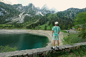 Boy stand against lake and mountains at Vorderer Gosausee, Gosau, Upper Austria.