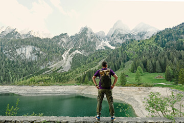 Back of man with backpack against lake and mountains at Vorderer Gosausee, Gosau, Upper Austria.