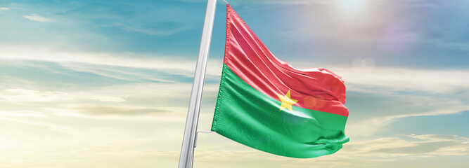 Waving Flag of Burkina Faso in Blue Sky. The symbol of the state on wavy cotton fabric. - obrazy, fototapety, plakaty