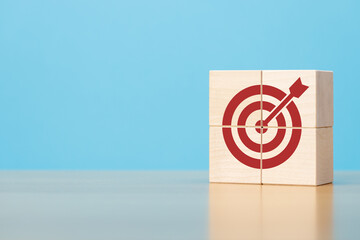 Wooden blocks with red target icon on wooden table blue background copy space. The concept of...