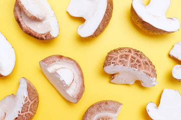 Cut shiitake mushrooms on yellow background close-up, top view.