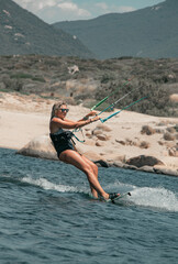 Woman kitesurfer leaning almost horizontally on her board to tack with her sail on the Mediterranean Sea in Corsica near Propriano