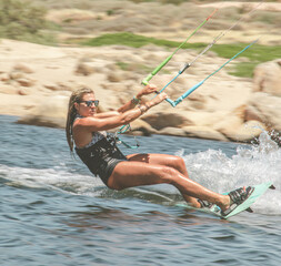 Female athlete kite-surfing on the Mediterranean Sea in Corsica near Propriano in full action, almost horizontal to the water