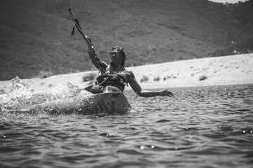 Female athlete kite-surfing on the Mediterranean Sea in Corsica near Propriano in full action, almost horizontal to the water