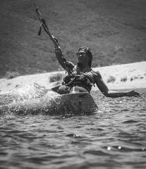 Female athlete kite-surfing on the Mediterranean Sea in Corsica near Propriano in full action, almost horizontal to the water