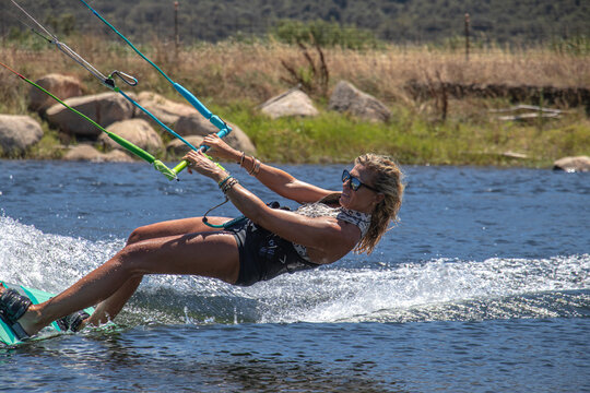 Woman kitesurfer leaning almost horizontally on her board to tack with her sail on the Mediterranean Sea in Corsica near Propriano