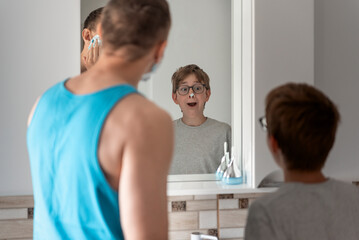 Dad and son in bathroom in front of mirror. Father and son shaving in bathroom together.