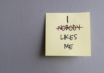Copy space wall with stick note written NOBODY LIKES ME (replace NOBODY with I) - concept of...