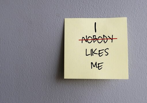 Copy space wall with stick note written NOBODY LIKES ME (replace NOBODY with I) - concept of overcome negative self talk and replace with positive affirmation to overcome inner self critic