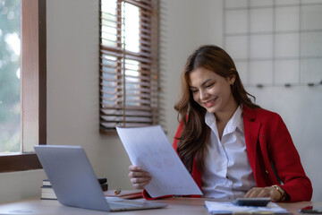 Asian Business woman using calculator and laptop for doing math finance on an office desk, tax,...