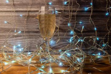 surface level of one glass of champagne on garland light background, christmas concept
