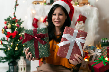Fototapeta na wymiar Beautiful woman with Christmas gift box, new year tree background, lights and beautiful decorations in a happy celebrating favorite holiday and holding some box of gift.