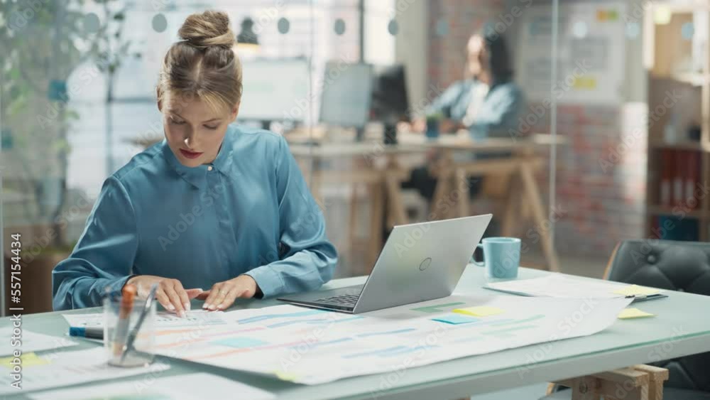 Poster portrait of white creative young woman working on a laptop computer in bright office. female team le