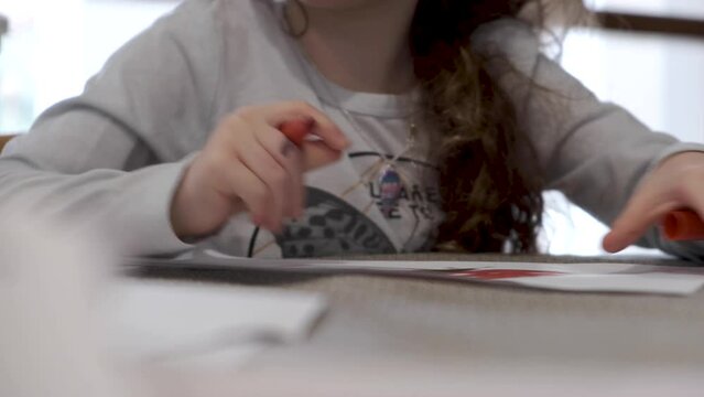 Little girl drawing on paper. Holding a red marker and coloring in. Kids are 4K