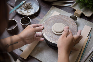 Close up hand of Asian Female using pottery wheel to make a tea pot in the workshop