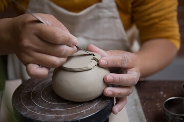 Close up hand of Asian Female using pottery wheel to make a tea pot in the workshop
