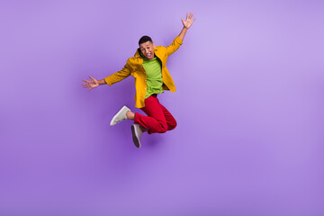Fototapeta na wymiar Full body photo of active overjoyed person jumping raise hands isolated on violet color background