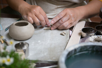Close up hand of Asian Female using pottery wheel to make a tea pot in the workshop