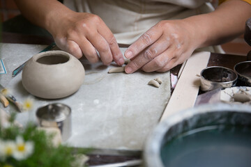 Fototapeta na wymiar Close up hand of Asian Female using pottery wheel to make a tea pot in the workshop