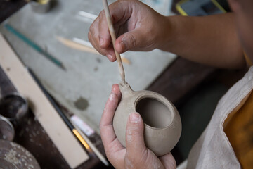 Close up hand of Asian Female using pottery wheel to make a tea pot in the workshop