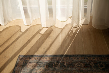 Fototapeta na wymiar Transparent white curtain tulle on a sunny day, rays of sunlight penetrate the room, view from inside