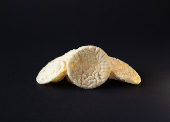 Puffed Potato Chips, Stacked on a plain black background with shadow, healthy potato snack.Puffed chis 
