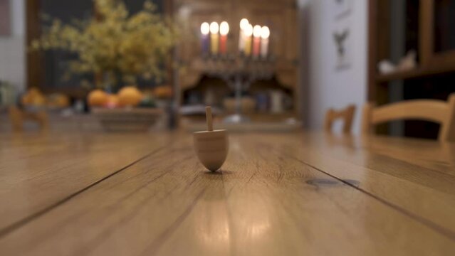 Hand spinning dreidel while Hanukah candles light in the background. Celebrating jewish holiday. Judaism tradition.