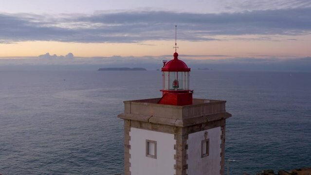 Coastal lighthouse. Aerial towards Waves crash over rocks aerial over island with lighthouse. Aerial fly over coastal lighthouse with waves crashing on the cliffside. Portugal. 