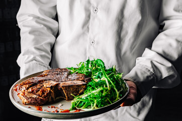 chef holding Porterhouse beef steak in hand