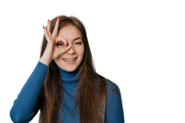 Young funky woman in blue sweater looking through ok sign made by hand over transparent background with copy space for ad. Fun and happy lifestyle. Mockup