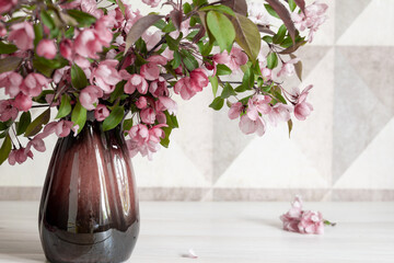 Beautiful seasonal composition of blossoming apple tree branches in a ceramic vase on a wooden table. Shallow depth of field