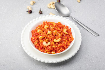 Fototapeta na wymiar Gajar ka halva is a traditional North Indian dessert made with freshly grated carrots, desi ghee, milk and sugar, delicately scented with cardamom and garnished with chopped nuts.