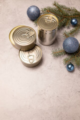 Christmas products, canned preservation, packed fish, meat or vegetables in can on concrete gray background with Christmas fir and toy balls. Copy space. New year food concept. Vertical
