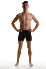 Front view. Portrait of mature handsome man with muscular body posing shirtless in black boxers over white studio background. Men's health and beauty