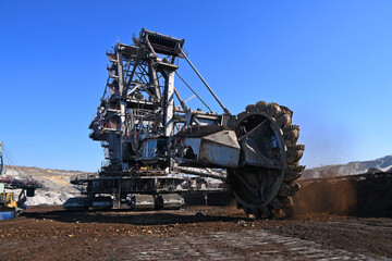 Fototapeta premium Bucket-wheel excavator during excavation at the surface mine. Huge excavator on open pit mine. 