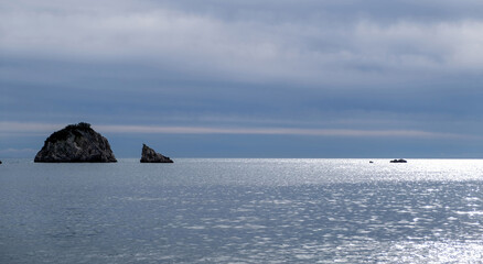 Blue cloudy sky and sea, aerial drone view. Small rock islands in endless blue.