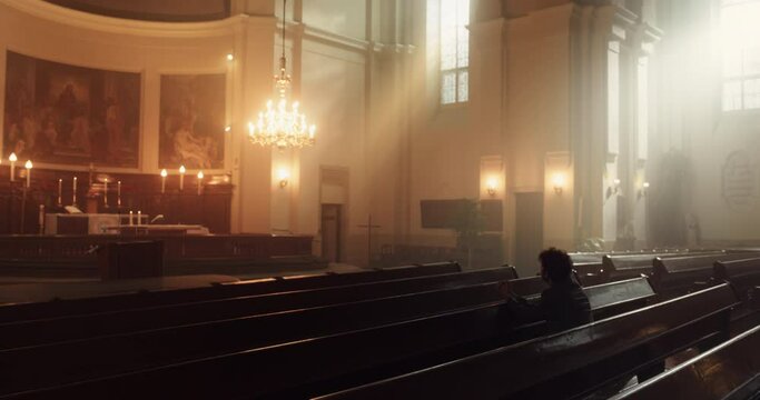 A Devout Christian Sits Piously In A Grand Church, Folding Hands For Praying, Seeks Guidance From Their Religious Faith and Spirituality. Spirit of Christianity and Belief in Power and Love of God