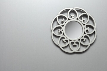 Gray MDF wall with a round mirror decorated with ornaments.