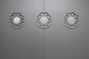 Gray MDF wall with a round mirror decorated with ornaments.