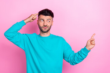 Photo of young dissatisfied pensive minded guy brunet hair finger temple head direct empty space bad choice company isolated on pink color background