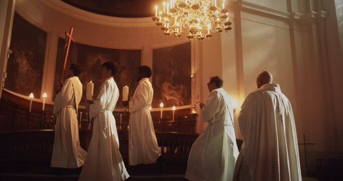 Liturgy in Grand Church: Majestic Procession Of Ministers, Priests Walking with Processional Cross to Altar. Congregation Stands In Reverence, Christians Rejoice In Mass Ceremony. Slow Motion Pan Shot