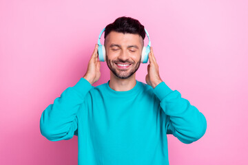 Portrait of cheerful satisfied person closed eyes hands touch headphones isolated on pink color background