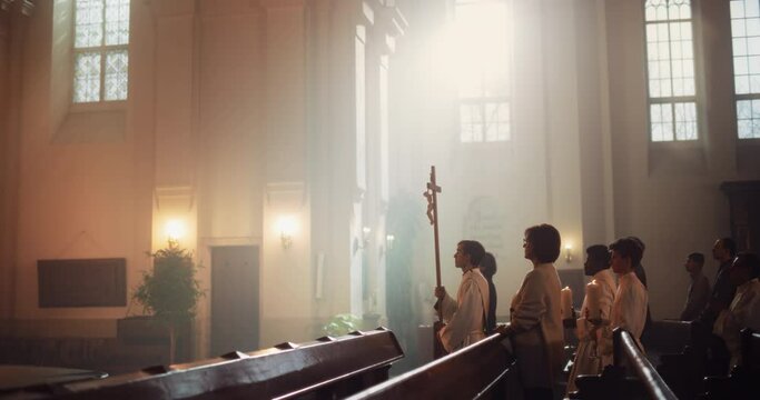 Liturgy in Grand Church: Majestic Procession Of Ministers, Priests Walking with Processional Cross to Altar. Congregation Stands In Reverence, Christians Rejoice In Mass Ceremony. Slow Motion Pan Shot