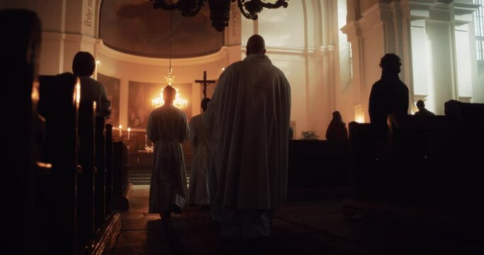 Liturgy in Grand Church: Majestic Procession Of Priests Walking with Processional Cross to Altar. Congregation Stands In Reverence, Christians Rejoice In Mass Ceremony. Slow Motion Back View