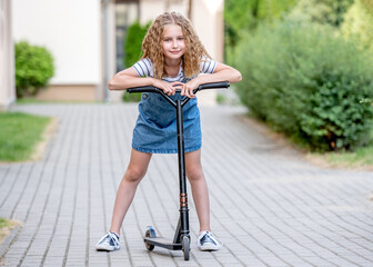 Naklejka premium Little girl rides a kick scooter