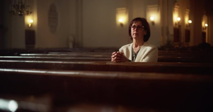 Portrait of a Pious Senior Woman Praying while Sitting in the Old Church. Parishioner Feeling Connection to Divinity. Hope, Belief in Salvation through Goodness, Kindness. Contemplation in Cathedral